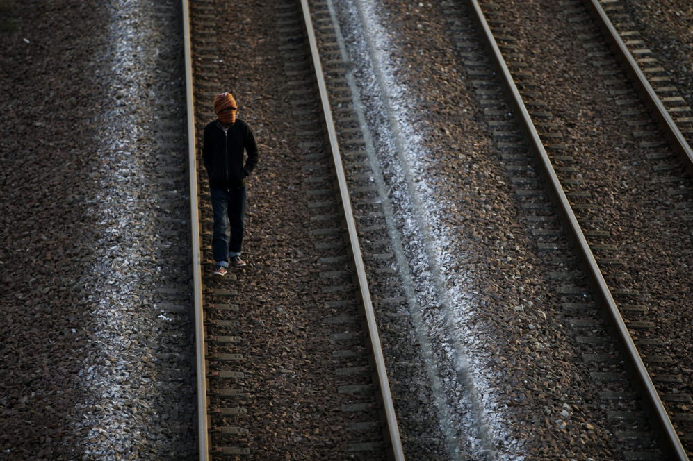 Un migrante camina por las vías antes de intentar coger un tren desde...