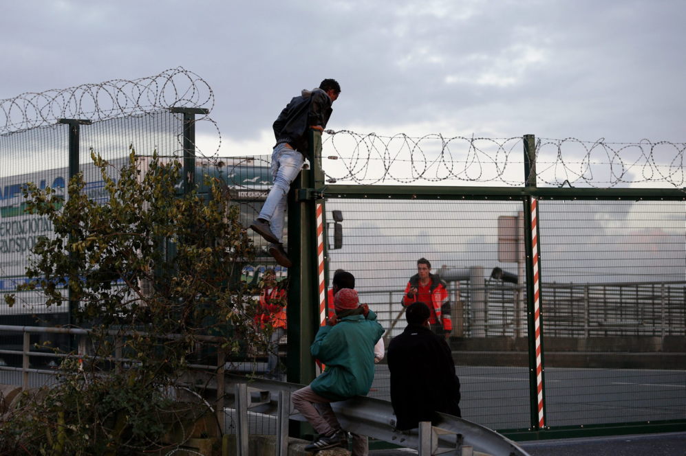 Un migrante salta la cerca para intentar coger un tren ante los...