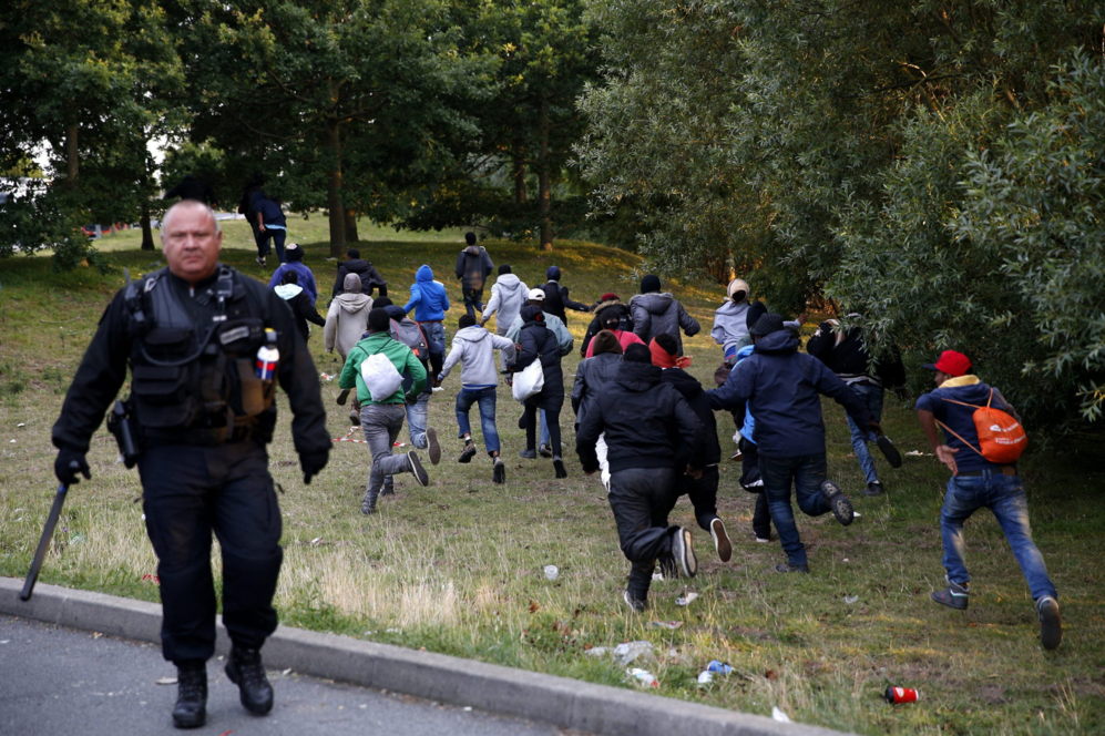 Varios migrantes huyen de la policía francesa, que han reforzado su...