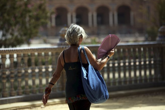 Una mujer pasea con un abanico por la Plaza de Espaa de Sevilla.