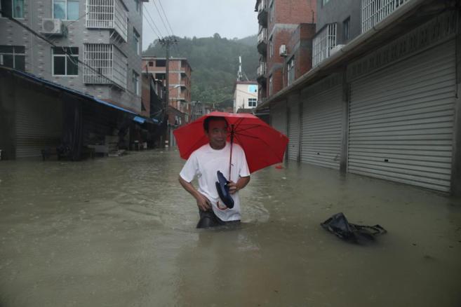 Un hombre camina por una calle inundada en Ningde, al sureste de la...