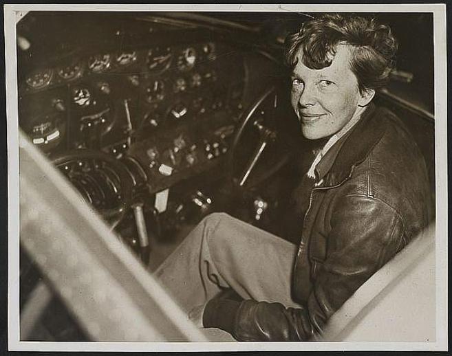Amelia Earhart, sentada en la cabina del piloto de su aeroplano...