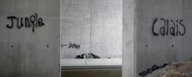 Un inmigrante duerme bajo un puente en Calais, en la entrada del...
