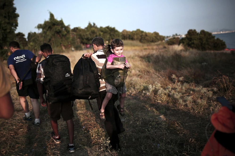 Un inmigrante lleva a su hija en la espalda tras cruzar el mar Egeo y...
