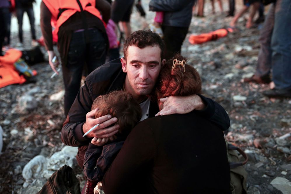 Un refugiado sirio abraza intensamente a su familia que descansa tras...