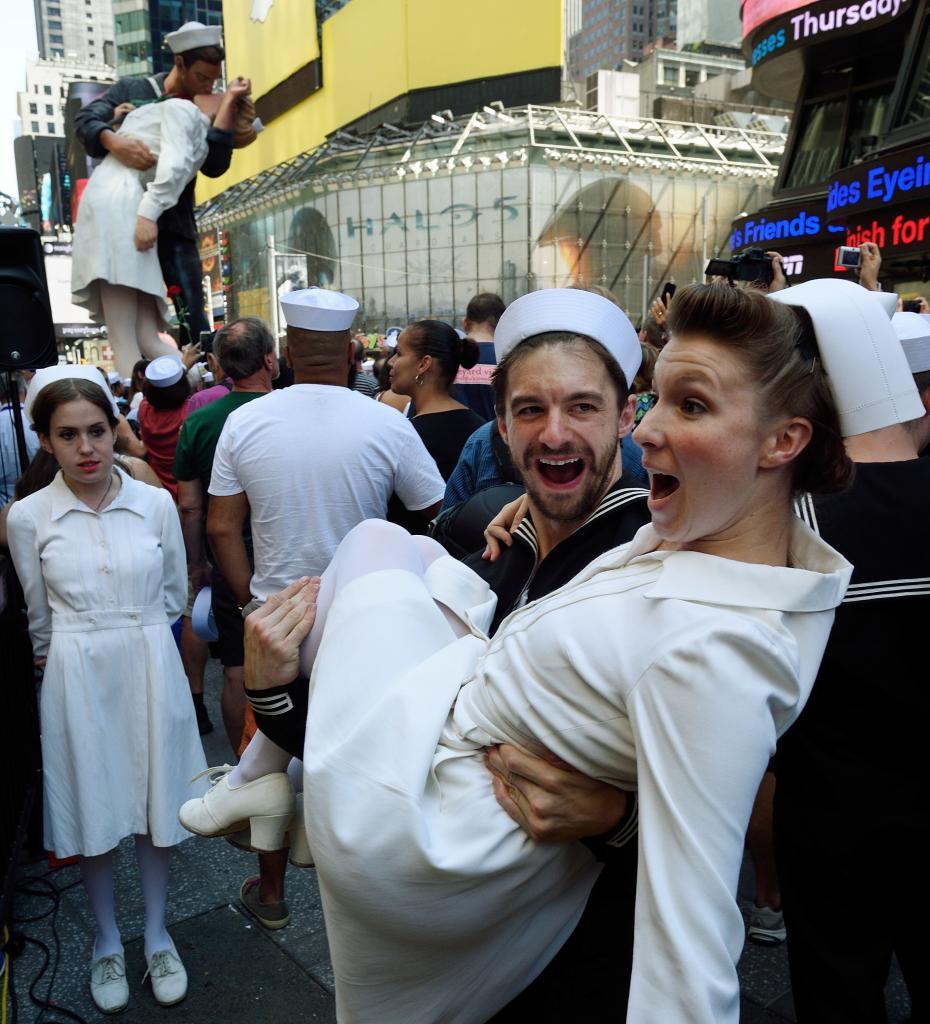 Un chico coge en brazos a su pareja en Times Square.