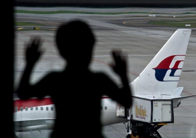 Un nio observa un avin de Malaysia Airlines.