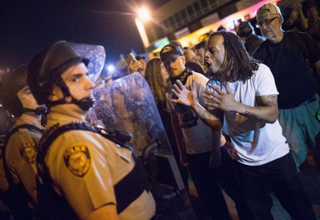 Un hombre protesta frente a un polica de Ferguson en el aniversario...