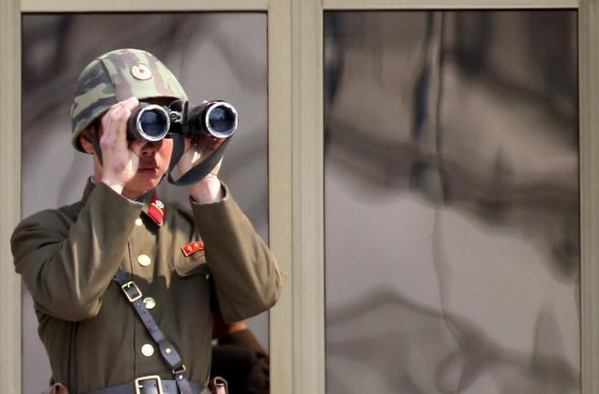 Un soldado norcoreano observa con sus binoculares la localidad de...