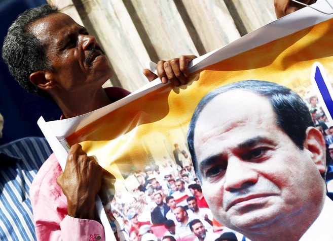 Un ciudadano egipcio sostiene una pancarta con la imgen de Al Sisi...