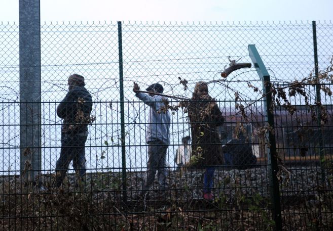 Tres niños inmigrantes esperan junto a las vías del Eurotúnel en...