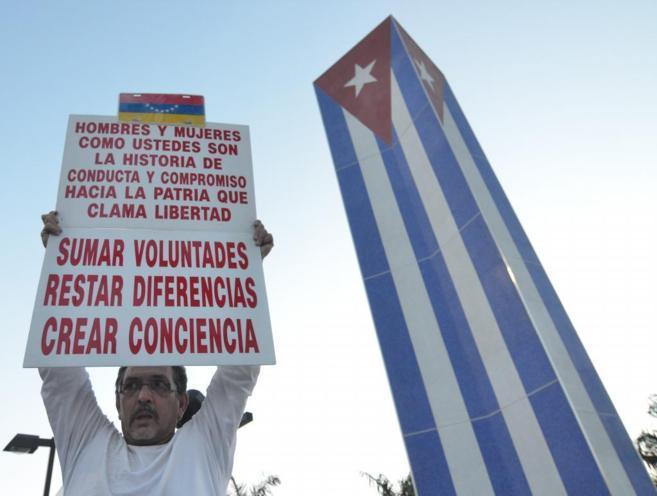 Un hombre levanta un cartel frente al Memorial Cubano levantado en...