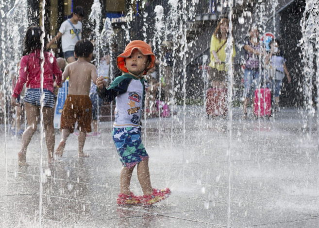 Un niño se refresca en Tokio durante la ola de calor que ha sufrido...