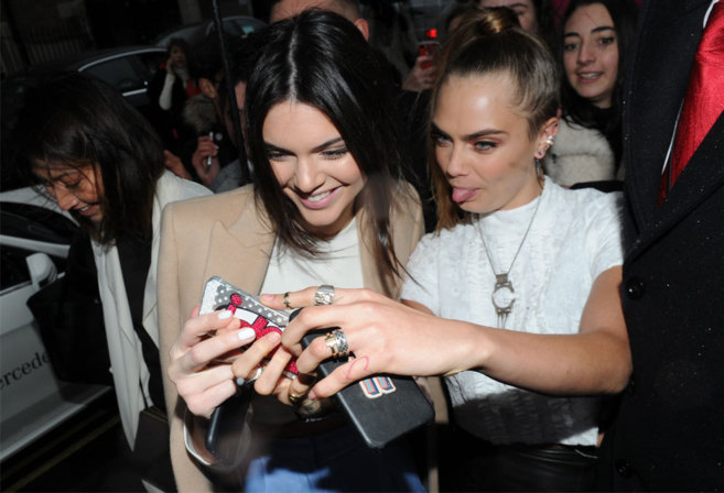 Kendall Jenner y Cara Delevingne atendiendo a sus respectivos...