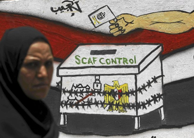 Una mujer delante de un grafiti que representa a la Junta Militar...