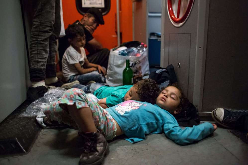 Nios refugiados duermen sobre el suelo de un tren procedente de...