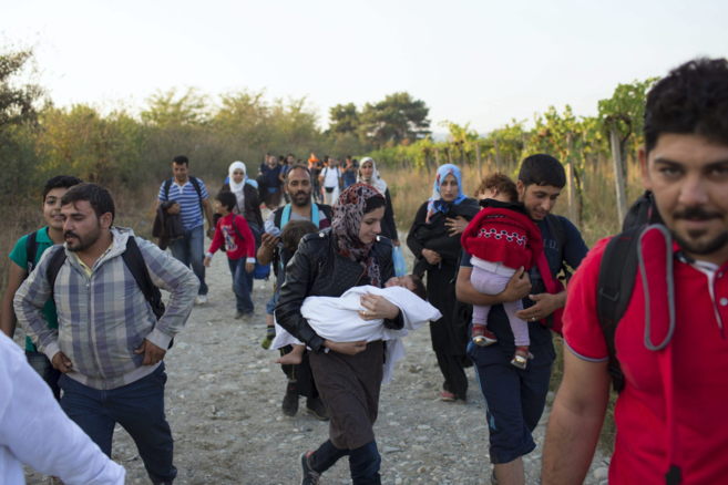 Un grupo de refugiados cruzan a pie la frontera entre Macedonia y...