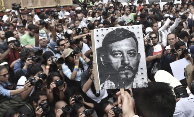 Periodistas mexicanos sostienen retratos de Espinosa durante una...