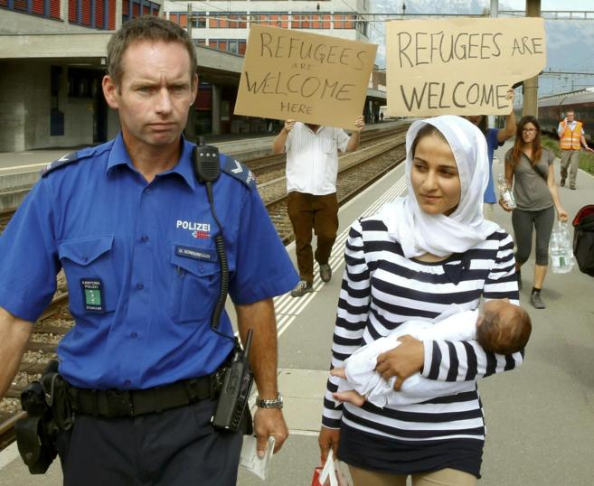 Un polica suizo acompaa a una inmigrante siria a su llegada a la...
