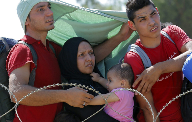 Una familia siria espera en la frontera entre Macedonia y Grecia.