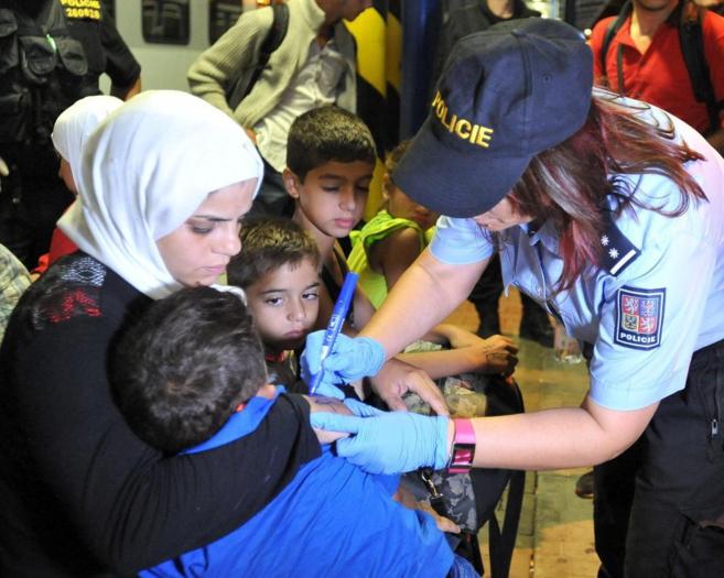 Una polica marca un nmero en el brazo de un refugiado sirio, en la...