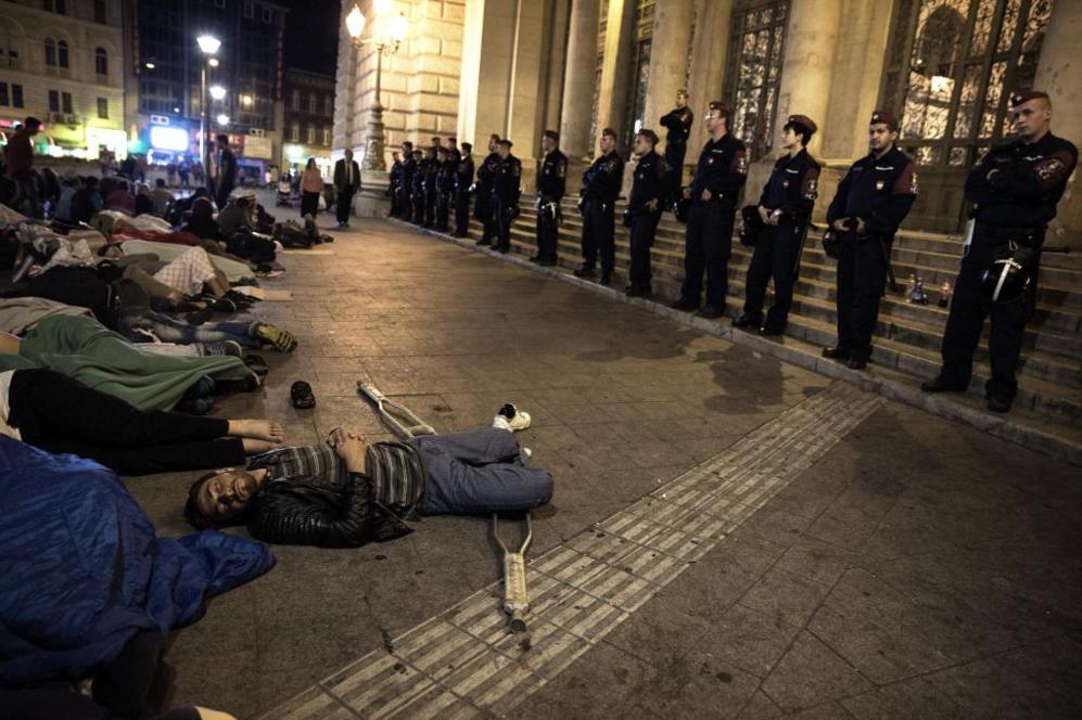 Un hombre herido descansa ante la mirada de las fuerzas de seguridad.