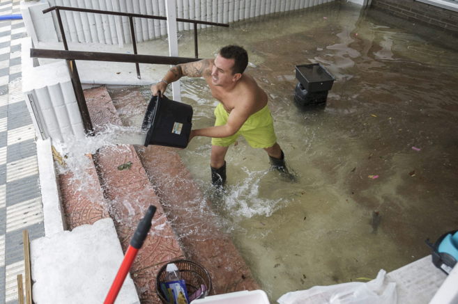 Un hombre achica agua en un bajo anegado por las lluvias.