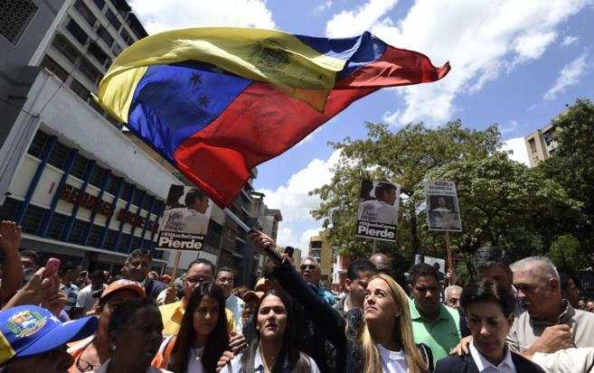 Lilian Tintori (centro) ondea la bandera nacional en Caracas mientras...
