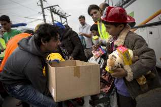 Un voluntario ofrece juguetes a un nio refugiado.