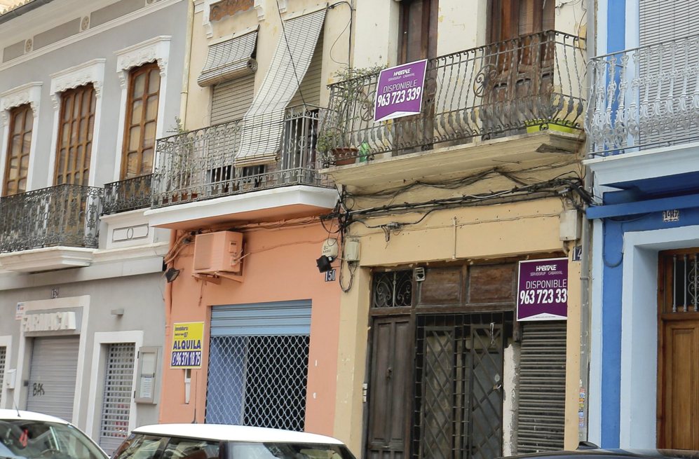 Una calle del barrio valenciano de El Cabanyal con varios carteles de...