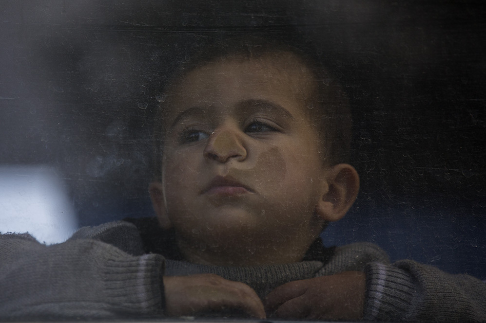 Un nio mira a travs de la ventana de un autobs de refugiados...