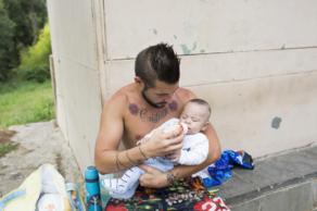 Un hombre da el bibern a su hijo en una calle de La Plvora.