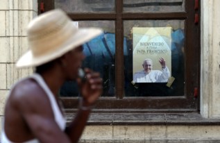 Un cubano, ante un retrato del Papa, que llega el sbado.