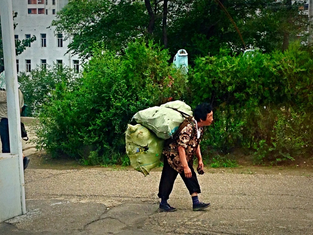 Una anciana cargada con sacos camina por un suburbio de Pyongyang.