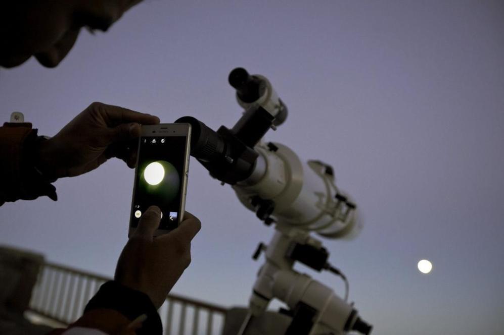 Un hombre fotografa, a travs de un telescopio, la superluna desde...