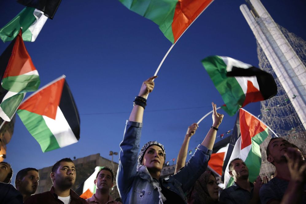 Palestinos agitan sus banderas nacionales mientras ven en directo el...