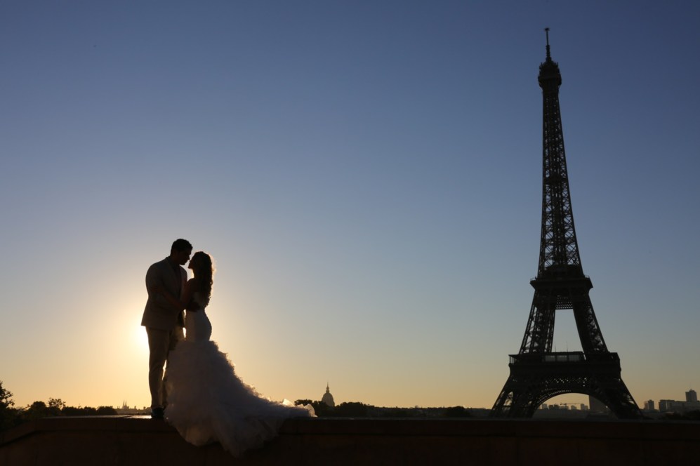 Un matrimonio joven posa para al amanecer en frente de la torre...