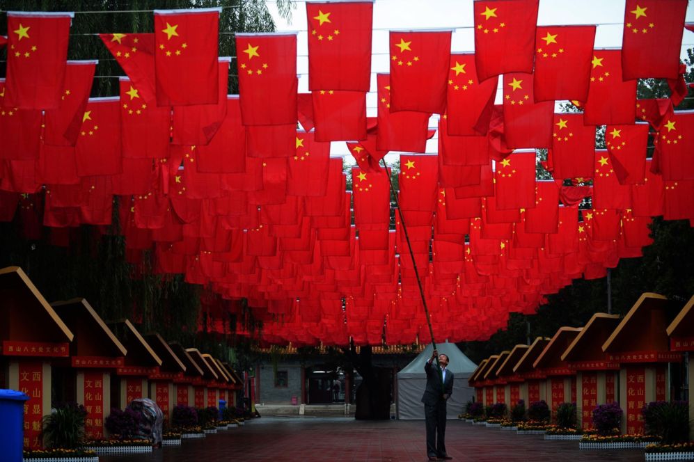 Un trabajador ajusta las banderas nacionales chinas despus de la...