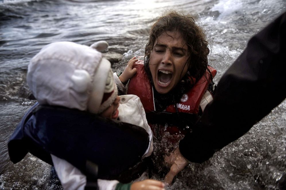 Una mujer cae en el agua con su hijo al desembarcan de una balsa en la...