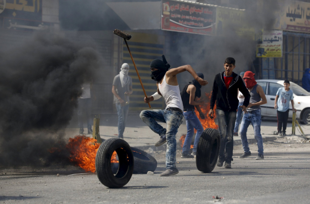 Un manifestante palestino camina corre entre neumticos ardiendo en...