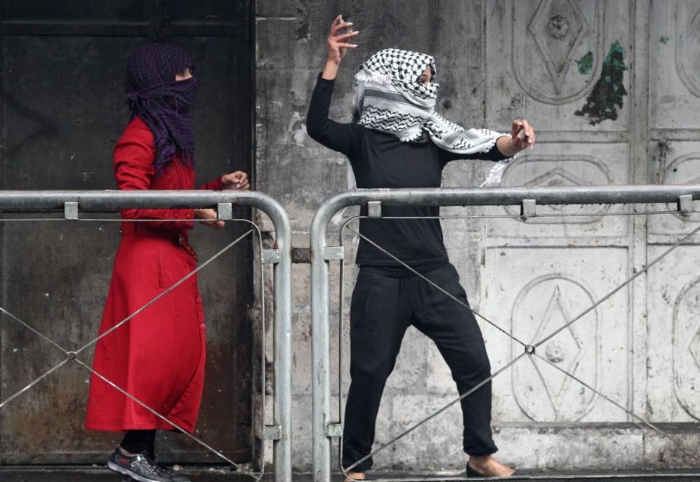 Una joven palestina lanza una piedra contra las fuerzas de seguridad...