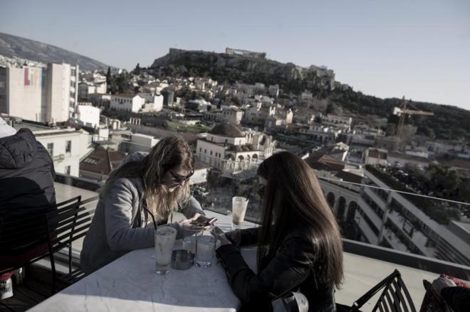 Dos jvenes en una cafetera junto a la Acrpolis de Atenas.