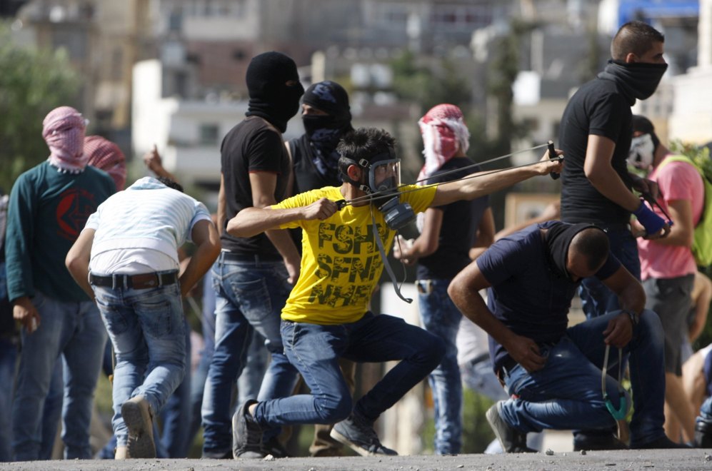 Un palestino utiliza un tirachinas para lanzar piedras a los soldados...
