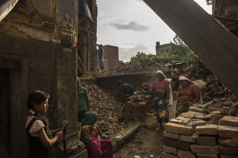 Ciudadanos del barrio de Bhaktapur trabajan entre los escombros para...