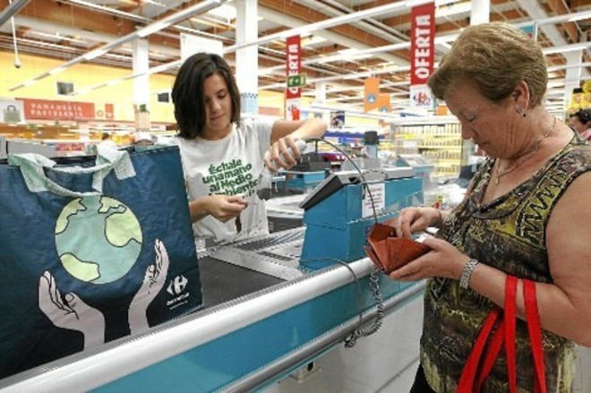 Una joven atiende a un cliente en la caja de un supermercado