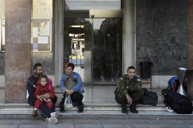 Griegos esperan en la entrada de la estación de tren, durante las 24...