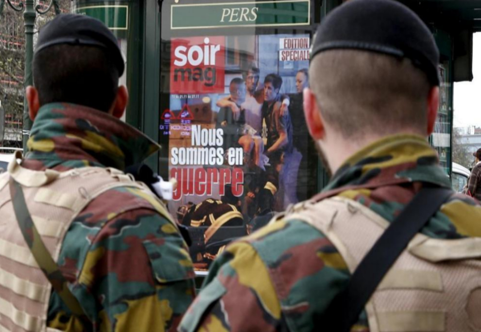 Dos soldados belgas observan la portada de una revista que titula...