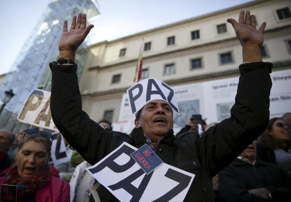 Un hombre con una pancarta pegada a la cabeza grita "no a la guerra".