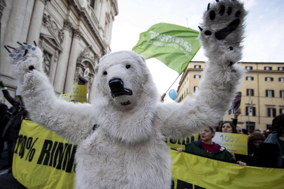 En Roma, un manifestante vestido de oso polar levanta los brazos.