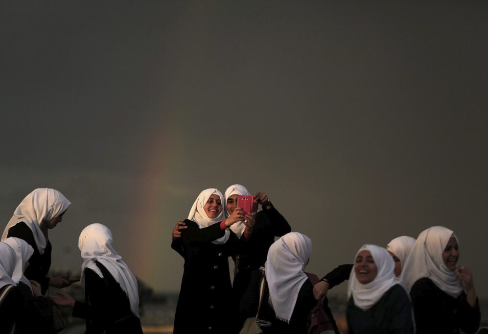 Estudiantes palestinas posan para un selfi con el arcoiris de fondo...